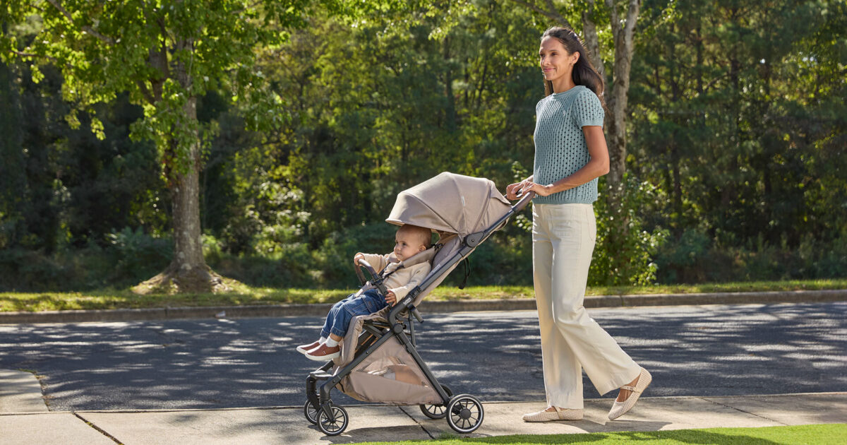 A mom walking outdoors with her baby in a compact stroller